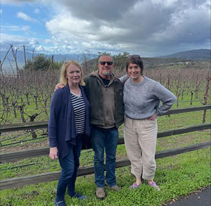 Guests at a vineyard fence among dormant vines at Aum Cellars